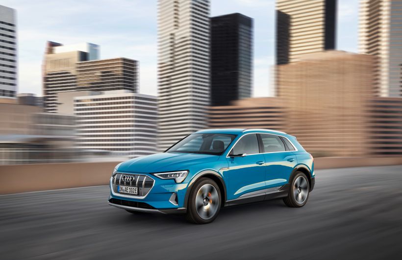 Blue Audi E-tron driving in city front and left side